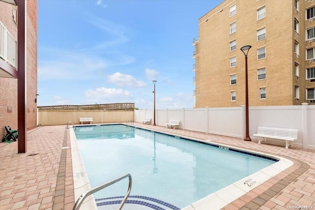 community pool with a patio area and fence