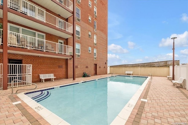 pool with a patio and fence