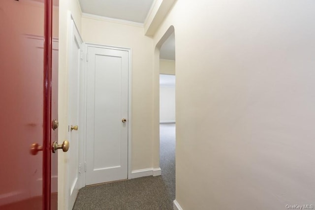 corridor with arched walkways, dark carpet, crown molding, and baseboards