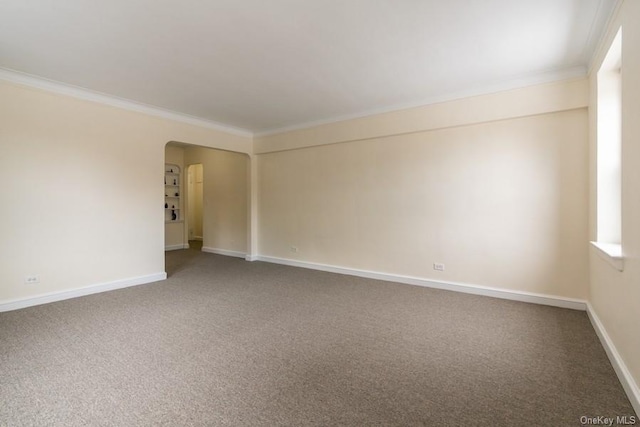 unfurnished room featuring arched walkways, baseboards, crown molding, and carpet