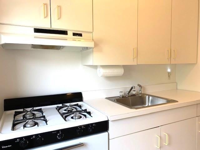 kitchen featuring light countertops, white gas stove, under cabinet range hood, and a sink