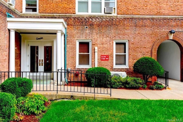 doorway to property featuring brick siding, cooling unit, and french doors