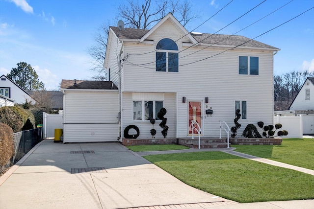 traditional-style house featuring a front yard, concrete driveway, fence, and a chimney