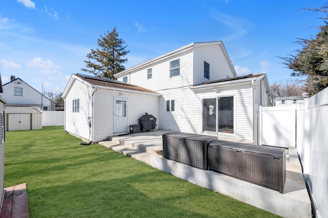 rear view of property with an outbuilding, a yard, a storage unit, a patio area, and a fenced backyard