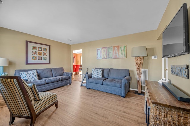 living room featuring baseboards, visible vents, and light wood finished floors