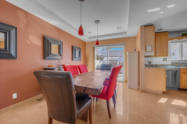 dining space featuring light tile patterned floors, a tray ceiling, and baseboards