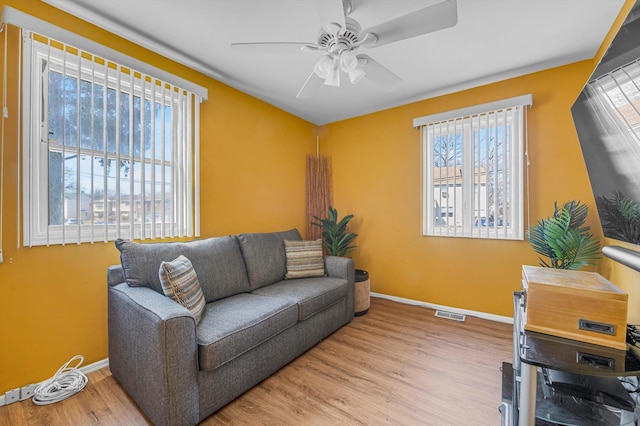 living room featuring baseboards, visible vents, ceiling fan, and wood finished floors