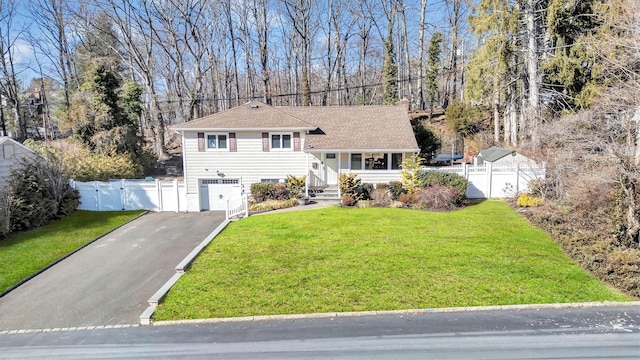 tri-level home with aphalt driveway, an attached garage, a front yard, a gate, and fence