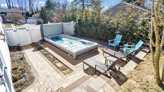 view of swimming pool featuring a patio, fence private yard, a gate, and a covered hot tub