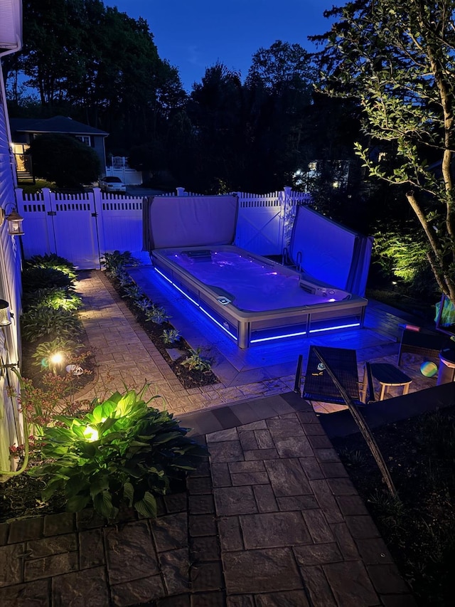 view of patio / terrace with a covered hot tub, a gate, and fence