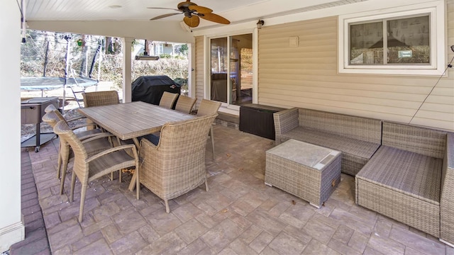 view of patio with a trampoline, outdoor dining space, a grill, and ceiling fan