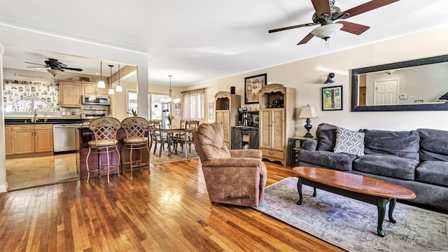 living room featuring ceiling fan with notable chandelier and light wood-style floors