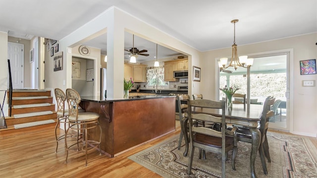 dining space with ceiling fan with notable chandelier, baseboards, and light wood-style floors