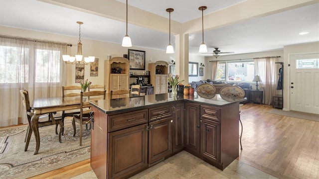 kitchen featuring dark countertops, light wood-type flooring, open floor plan, and hanging light fixtures