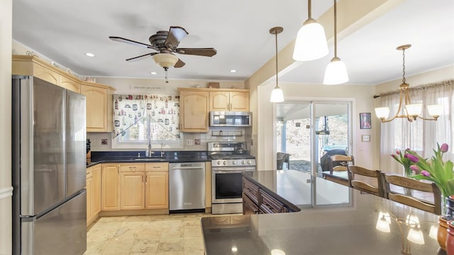 kitchen featuring stainless steel appliances, dark countertops, light brown cabinets, and a healthy amount of sunlight