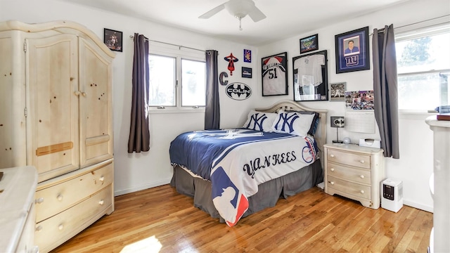 bedroom with a ceiling fan, baseboards, multiple windows, and light wood finished floors