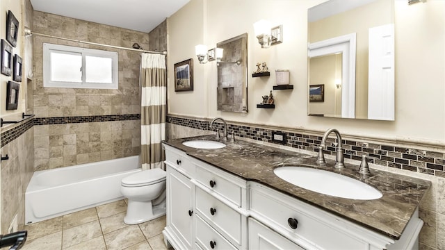 bathroom featuring toilet, shower / bath combo, a sink, and tile walls