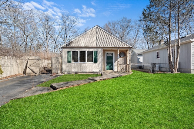 view of front of house featuring a gate, fence, driveway, and a front lawn