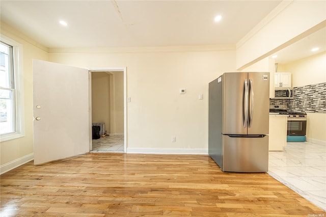 kitchen with radiator heating unit, ornamental molding, stainless steel appliances, and backsplash