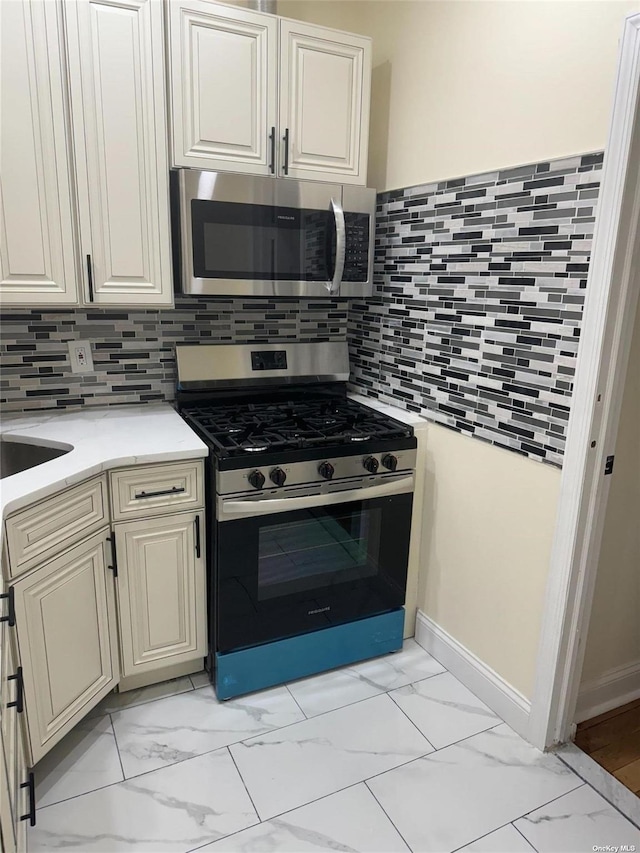 kitchen featuring appliances with stainless steel finishes, marble finish floor, backsplash, and light stone counters