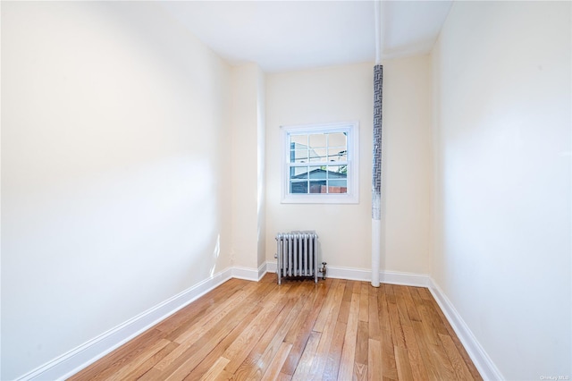 unfurnished room featuring light wood-type flooring, radiator heating unit, and baseboards