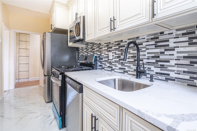 kitchen featuring light stone counters, a sink, marble finish floor, appliances with stainless steel finishes, and decorative backsplash