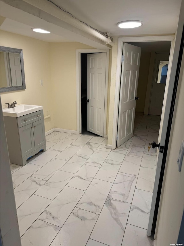 bathroom featuring marble finish floor, vanity, and baseboards