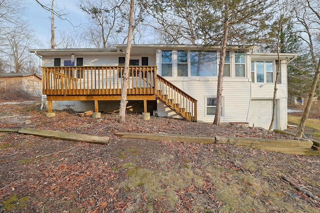 rear view of property with stairway, an attached garage, and a wooden deck