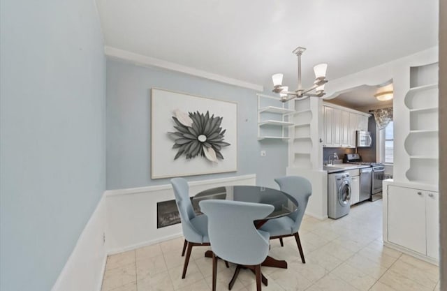 dining space featuring baseboards, washer / dryer, and an inviting chandelier