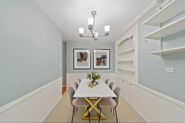 dining room featuring built in features, a notable chandelier, and wainscoting