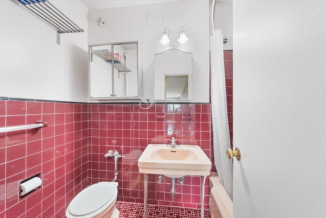 bathroom featuring a wainscoted wall, tile walls, and toilet