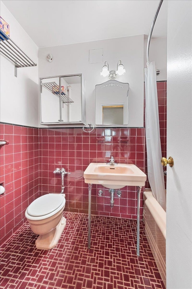 full bathroom with toilet, shower / bath combo, wainscoting, and tile walls