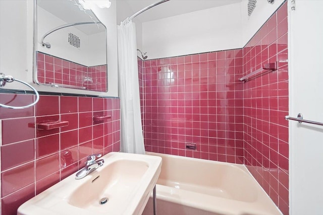 bathroom featuring a sink, tile walls, and shower / bathtub combination with curtain