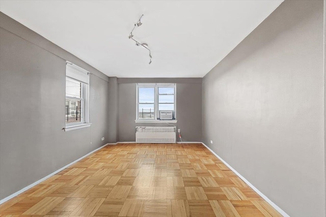 empty room featuring track lighting, radiator heating unit, and baseboards