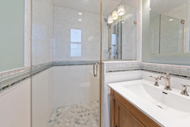 bathroom featuring vanity, a shower stall, and tile walls