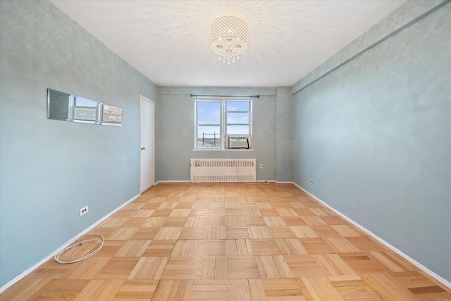 empty room with a chandelier, cooling unit, radiator, and baseboards