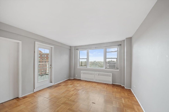 spare room with radiator, plenty of natural light, baseboards, and cooling unit