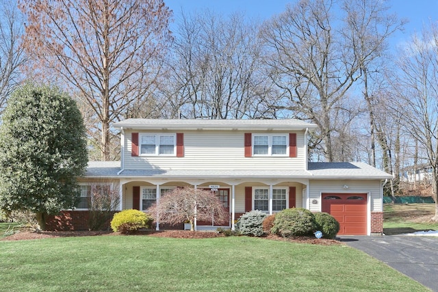 traditional-style house with driveway, a front lawn, an attached garage, and brick siding