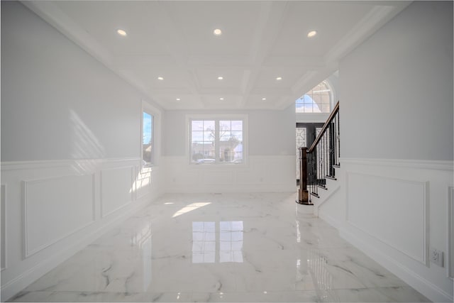 unfurnished living room featuring marble finish floor, a decorative wall, stairway, coffered ceiling, and beamed ceiling