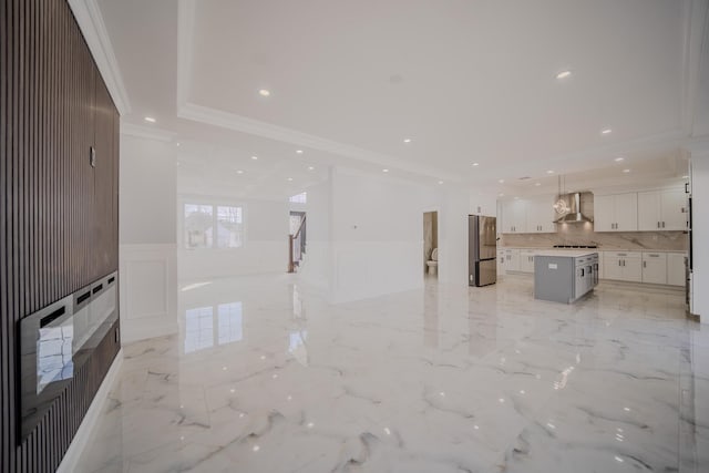 unfurnished living room with recessed lighting, a decorative wall, marble finish floor, ornamental molding, and wainscoting