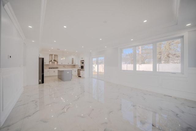 unfurnished living room with ornamental molding, marble finish floor, a wainscoted wall, and a decorative wall