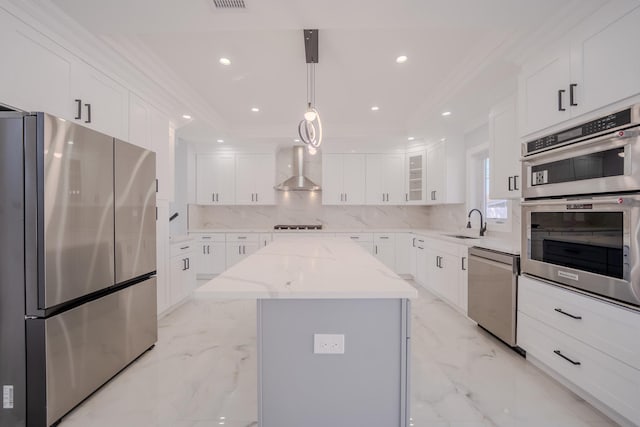 kitchen with a kitchen island, appliances with stainless steel finishes, marble finish floor, wall chimney range hood, and a sink