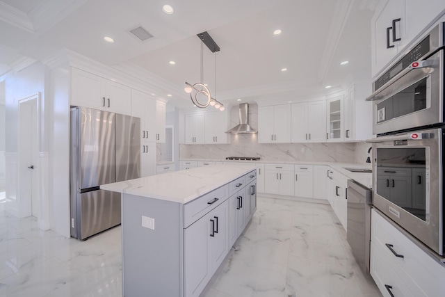 kitchen with a center island, marble finish floor, crown molding, stainless steel appliances, and wall chimney exhaust hood