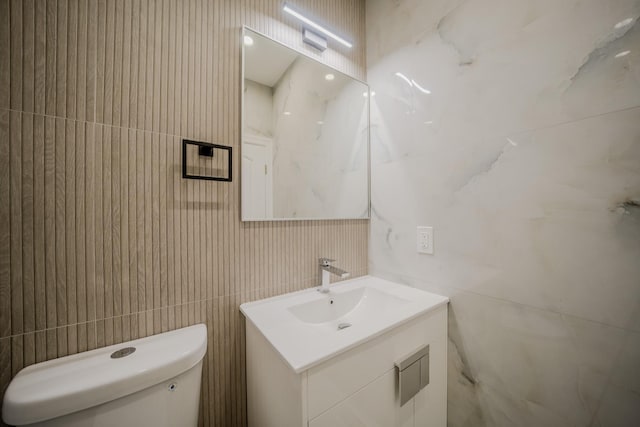 bathroom featuring tile walls, vanity, and toilet
