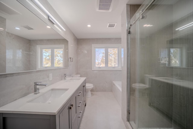 bathroom with a healthy amount of sunlight, a sink, tile walls, and toilet