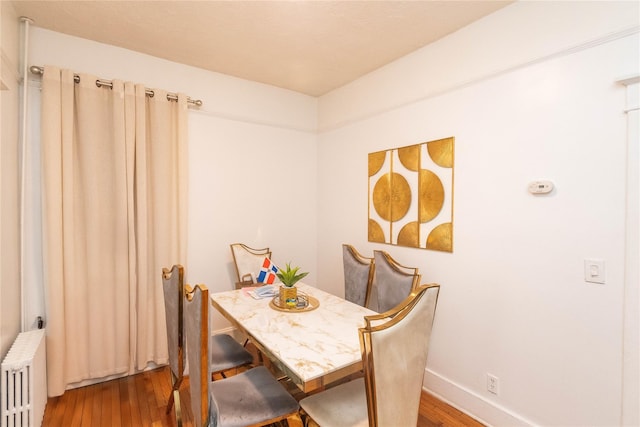 dining space with baseboards, radiator heating unit, and wood finished floors