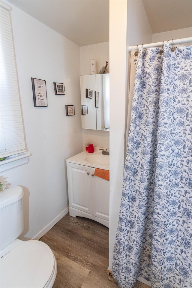 full bath featuring a shower with shower curtain, toilet, vanity, wood finished floors, and baseboards