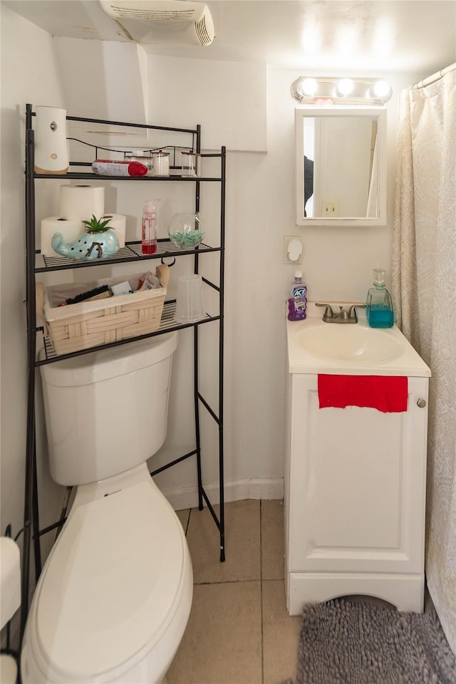 bathroom featuring baseboards, vanity, toilet, and tile patterned floors