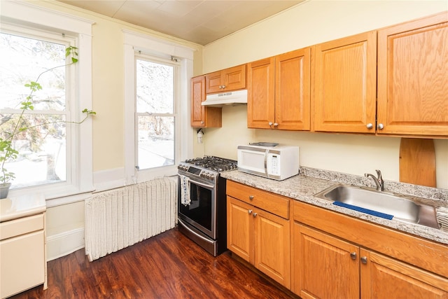 kitchen with radiator, white microwave, stainless steel range with gas stovetop, a sink, and under cabinet range hood