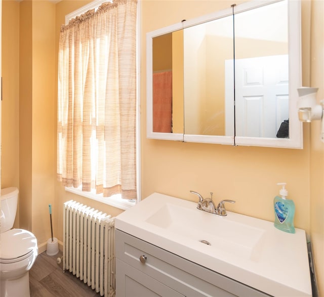 bathroom featuring toilet, radiator heating unit, wood finished floors, and vanity